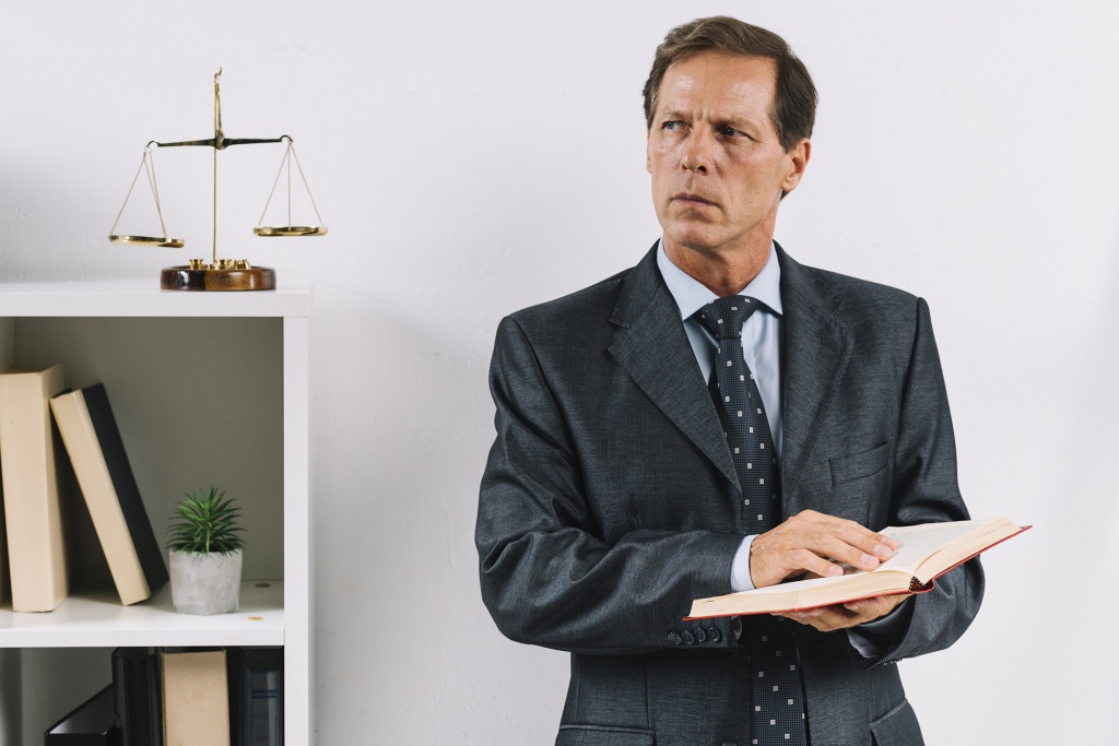 mature-male-lawyer-holding-law-book-standing-courtroom.jpg