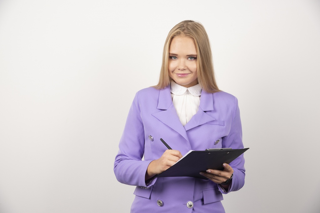 portrait-of-smiling-business-woman-standing-and-holding-clipboard.jpg