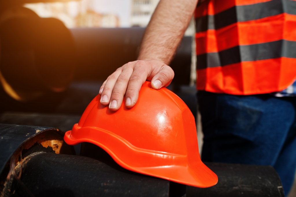 hand-of-worker-man-in-safety-orange-helmet-near-steel-pipes.jpg