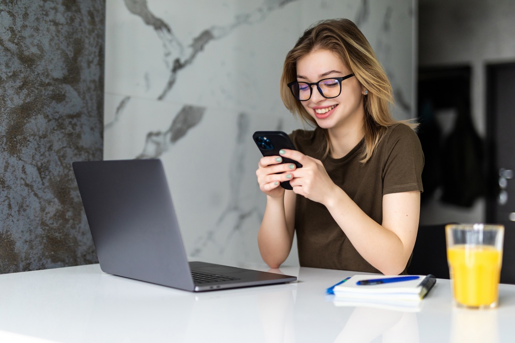 young-pretty-woman-sits-kitchen-table-using-laptop-use-cell-phone.jpg