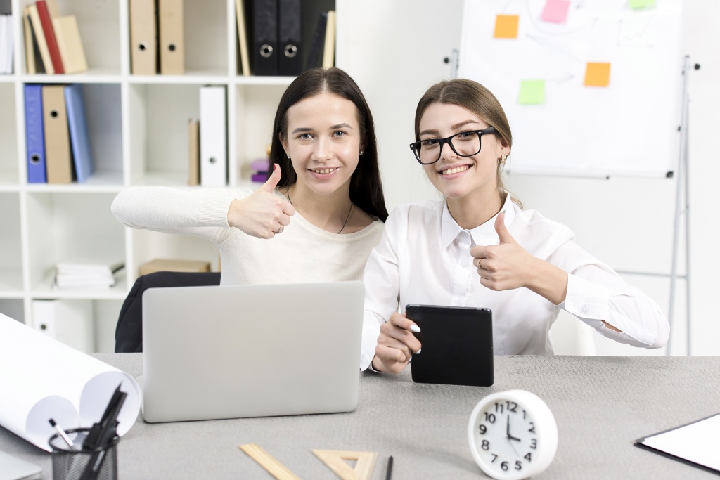 smiling-young-businesswoman-with-laptop-digital-tablet-showing-thumb-up-sign-workplace.jpg